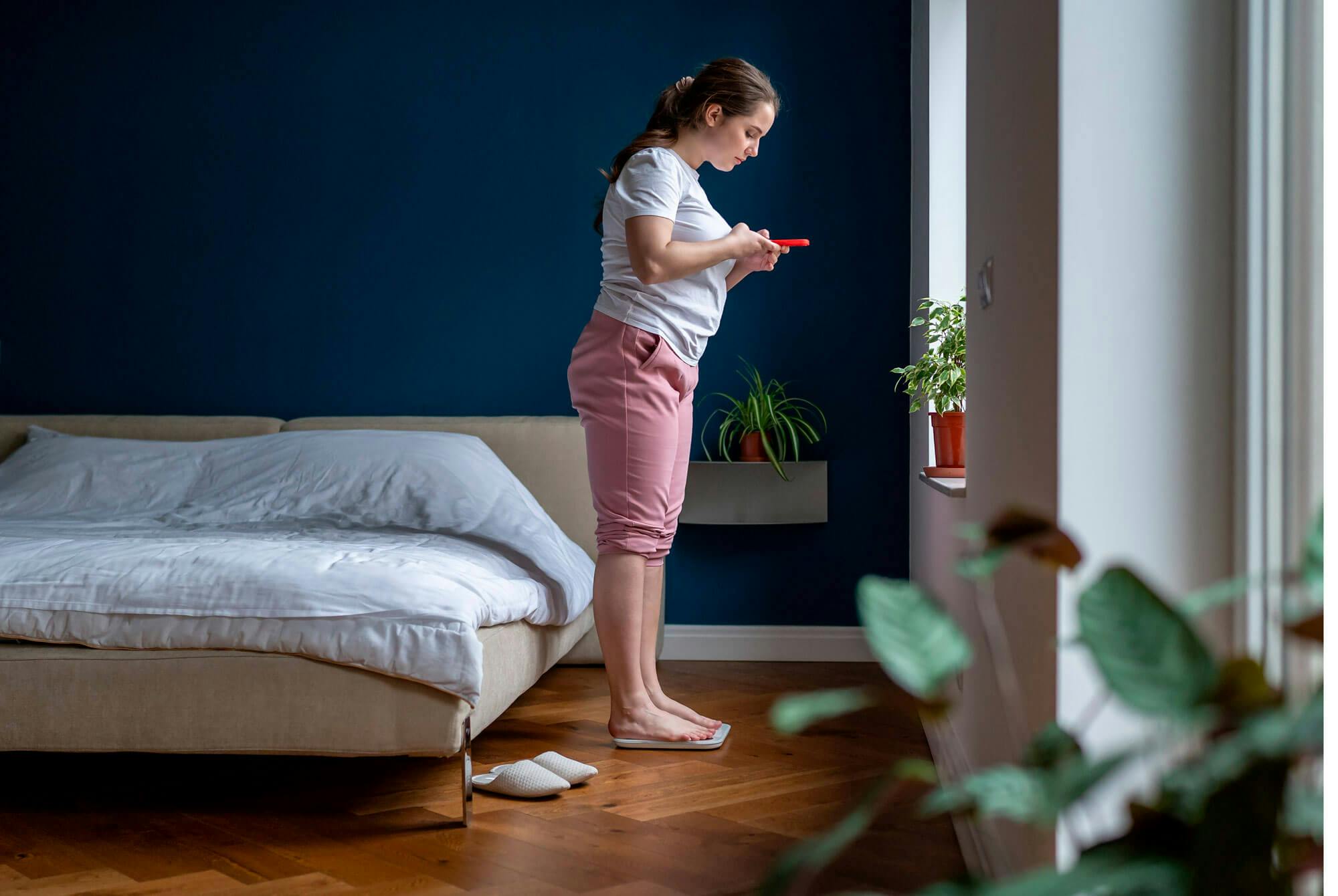 Jumahtiko painonpudotus? Nainen seisoo makuuhuoneessa vaa'alla.